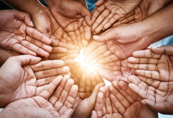 many people's cupped hands touching the sunlight.